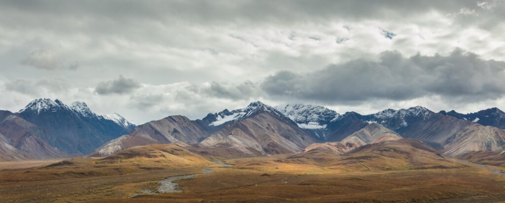 Ochre tundra and mountains in Denali National Park under a cloudy sky, seen from the Eielson Visitor Center