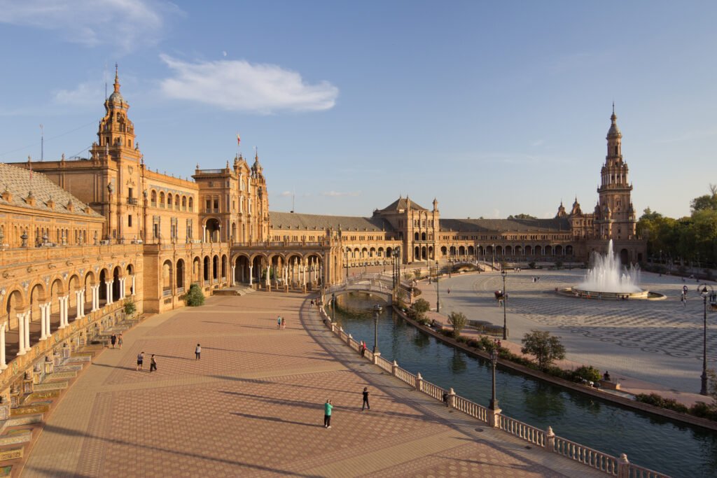 Plaza de España in Seville, with its semicircular building, towers, and canal under a blue sky