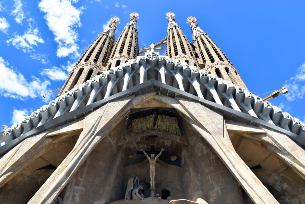 The Passion facade and towers of the Sagrada Família in Barcelona, seen from below against a blue sky